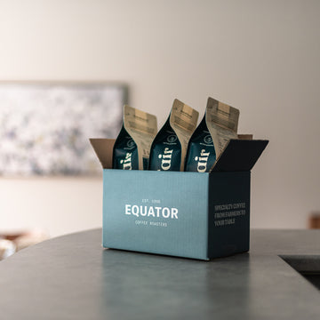 Three bags of coffee in a box on a counter.