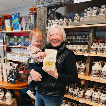 Shirley Fulton-Deugo and her grandchild holding a bag of Sweet Justice coffee in her store.
