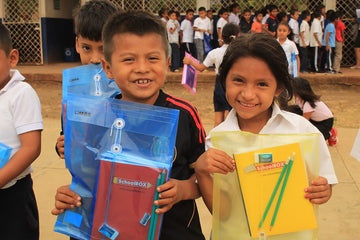Two smiling children from Nicaragua holding school supplies donated to them by SchoolBox.