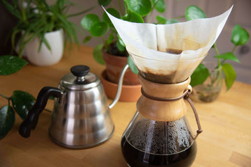 A stovetop kettle beside a Chemex with coffee in it.