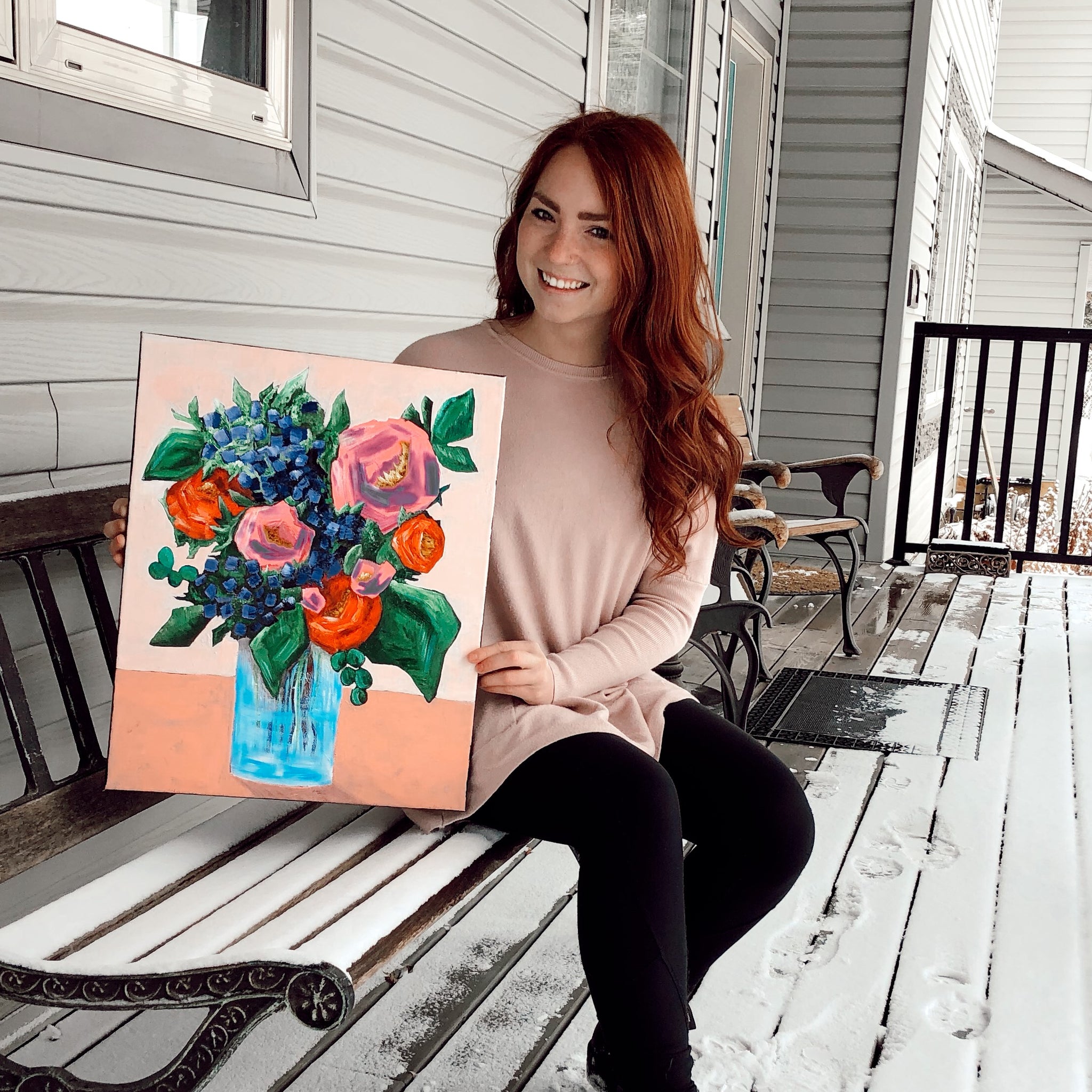 Bailey holding a painting she did of a jar of flowers.