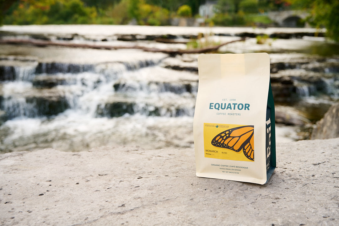A bag of Monarch blend coffee with a small waterfall in the background.